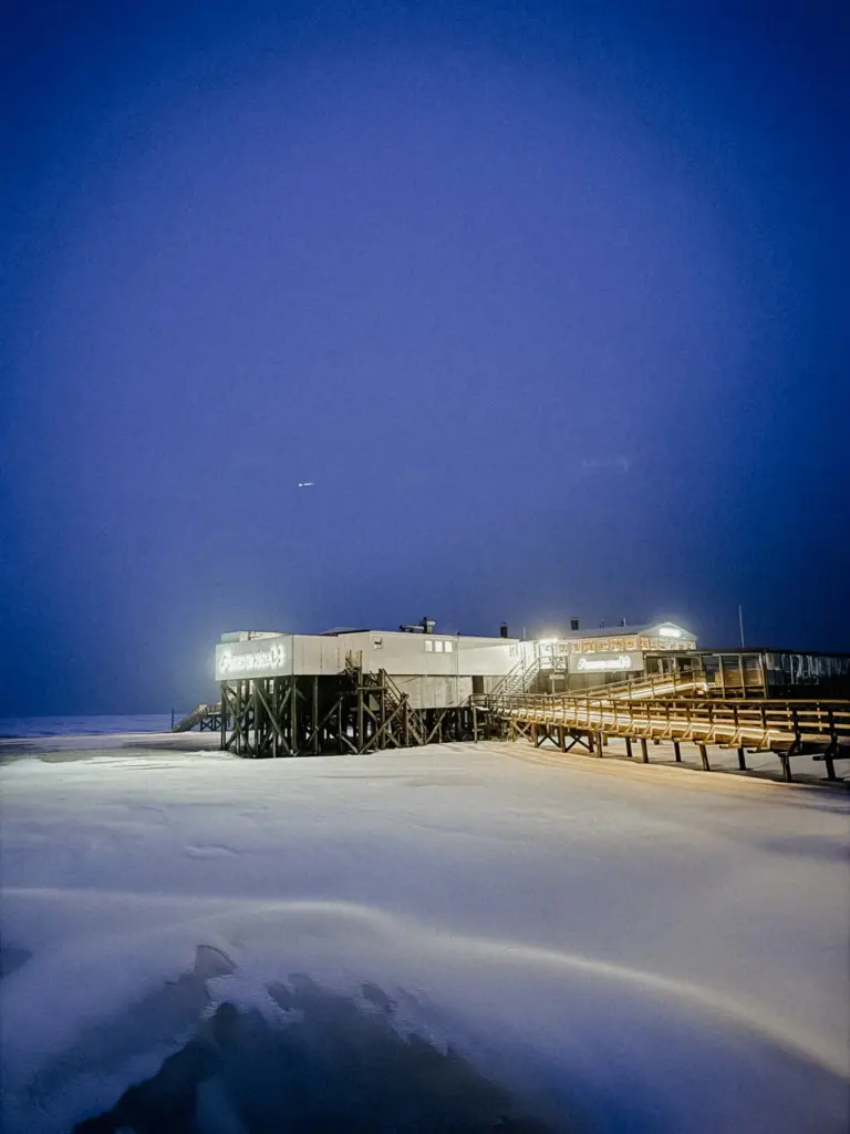Beleuchteter Pfahlbau an der Nordsee im Winter am Abend