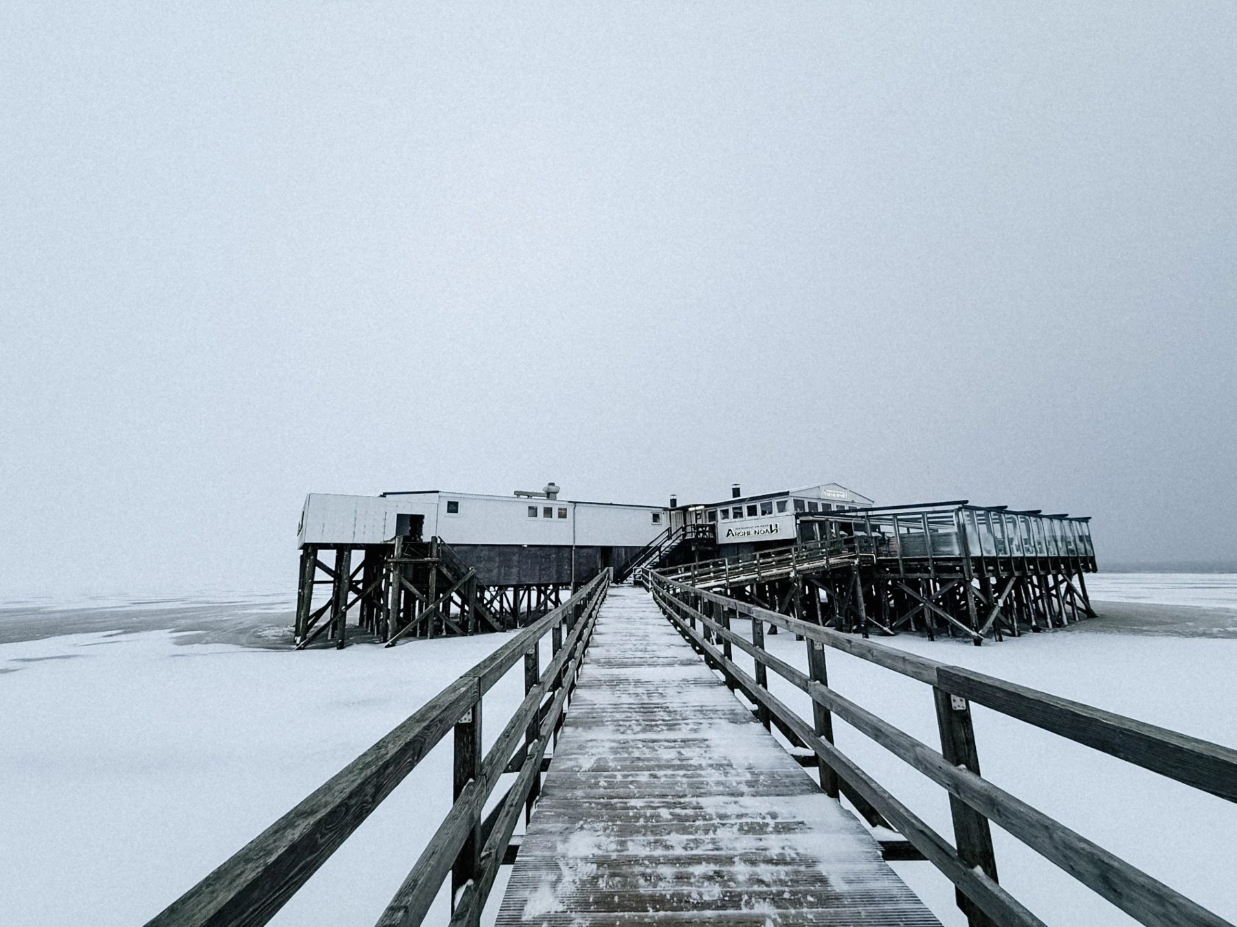 Verschneiter Holzsteg zum Restaurant Arche Noah an der Nordsee im Winter