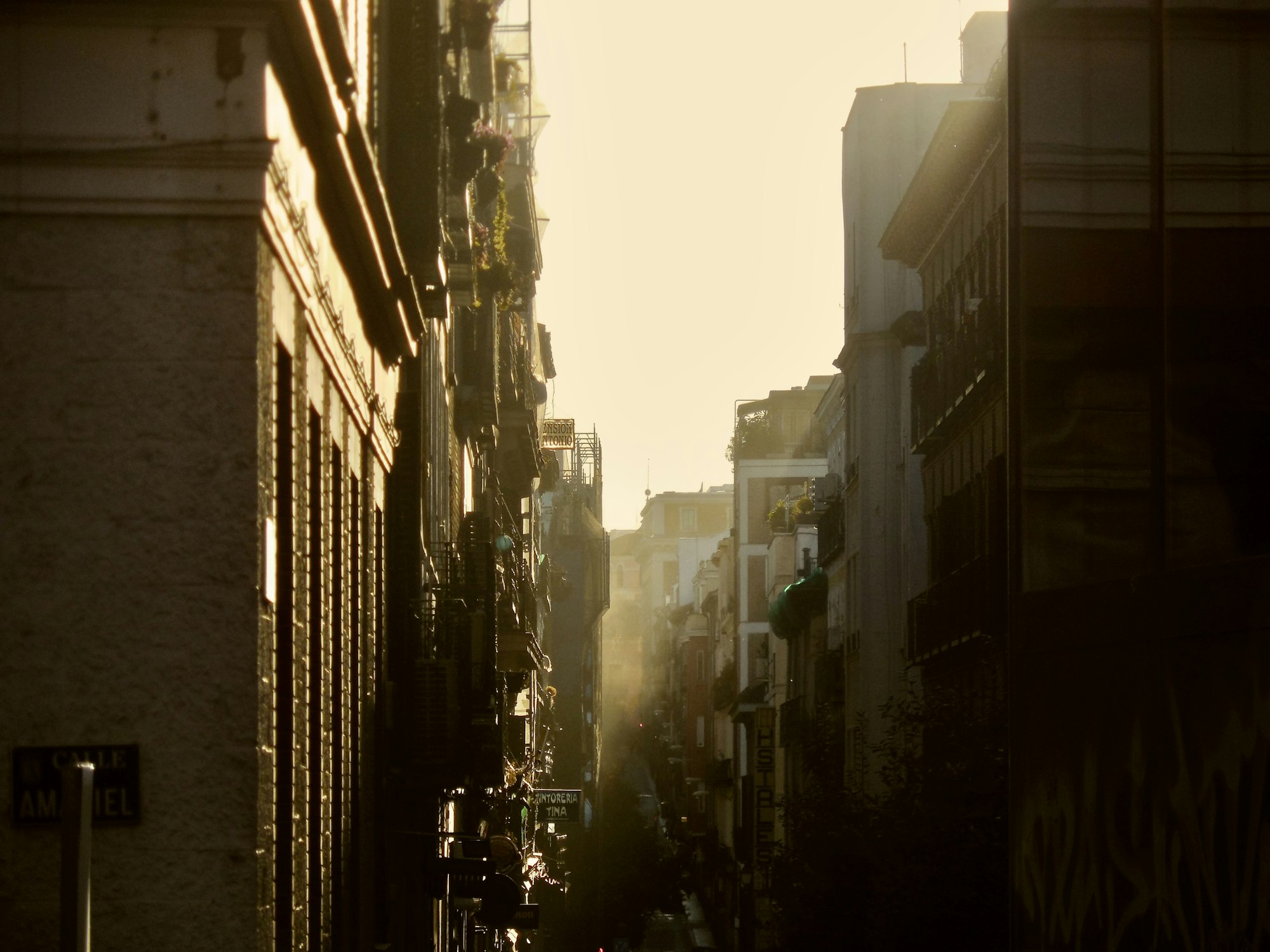 Morgensonne fällt durch eine enge Gasse in Madrid – ruhige europäische Straße ohne Touristen, Slow Travel Atmosphäre