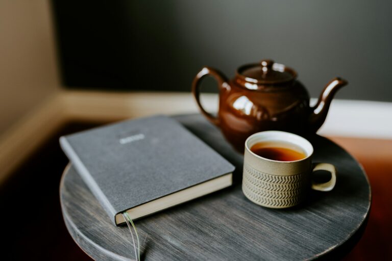 Eine Tasse Tee und ein aufgeschlagenes Buch auf einem Holztisch im warmen Morgenlicht