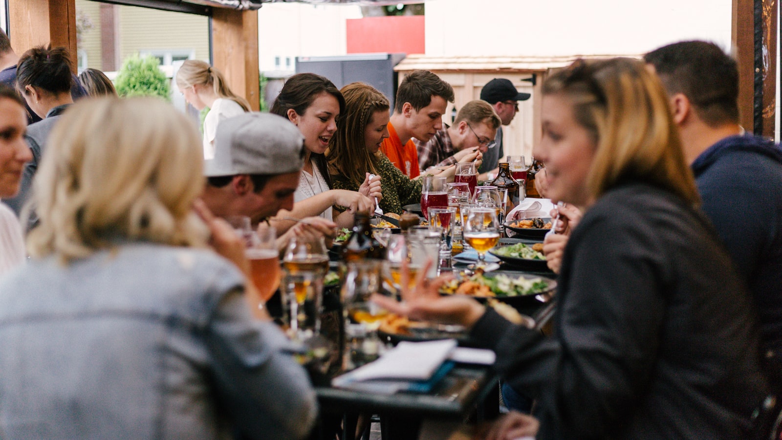 Menschen sitzen zusammen am Tisch beim Essen und lachen – soziale Verbindungen als stärkster Longevity-Faktor