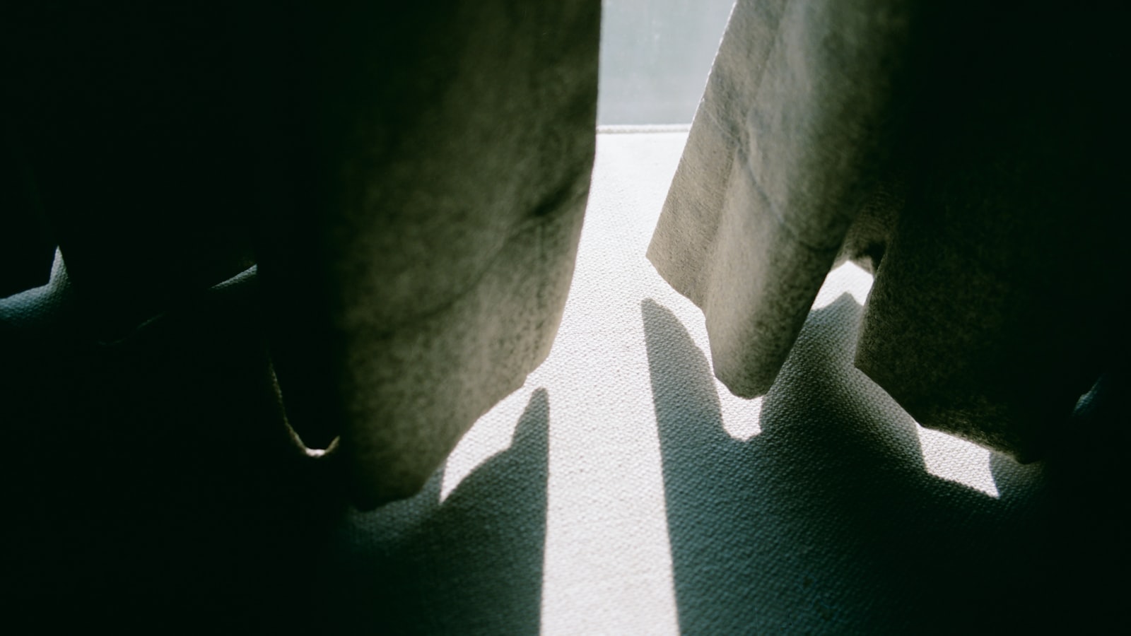 Sonnenlicht fällt durch geöffnete Vorhänge und wirft Schatten im Zimmer — Hitzeschutz durch Beschattung